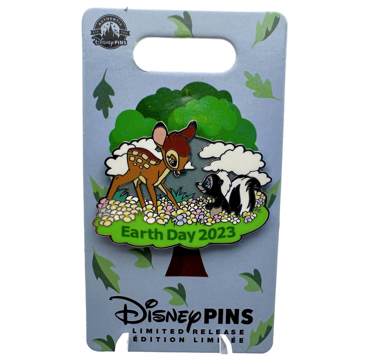 A Disney Pins Earth Day 2023 enamel pin featuring Bambi and Flower the skunk under a tree, mounted on a light blue display card with Disney Pins branding.